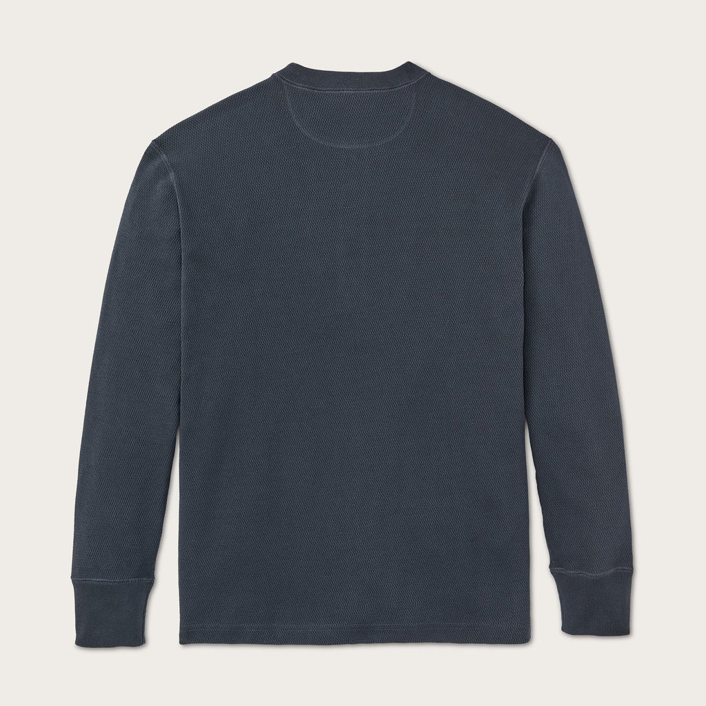 A dark slate blue long-sleeve crewneck shirt laid flat against a light beige background.