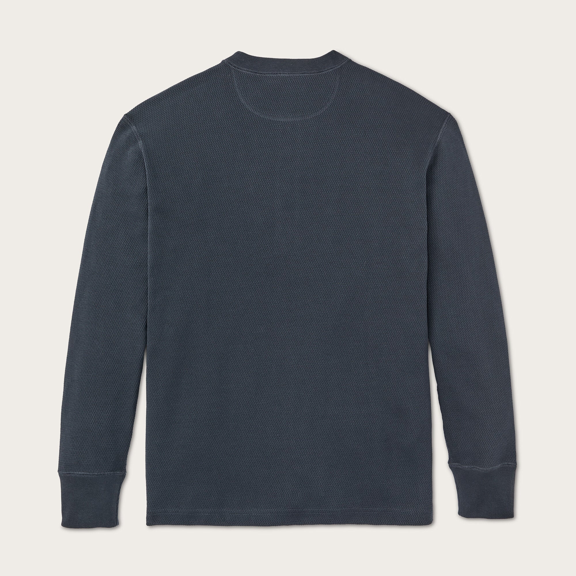 A dark slate blue long-sleeve crewneck shirt laid flat against a light beige background.