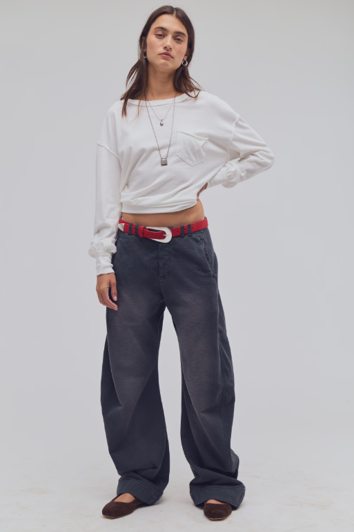Woman modeling black wide leg pants with red belt, white long sleeve t-shirt and brown shoes.