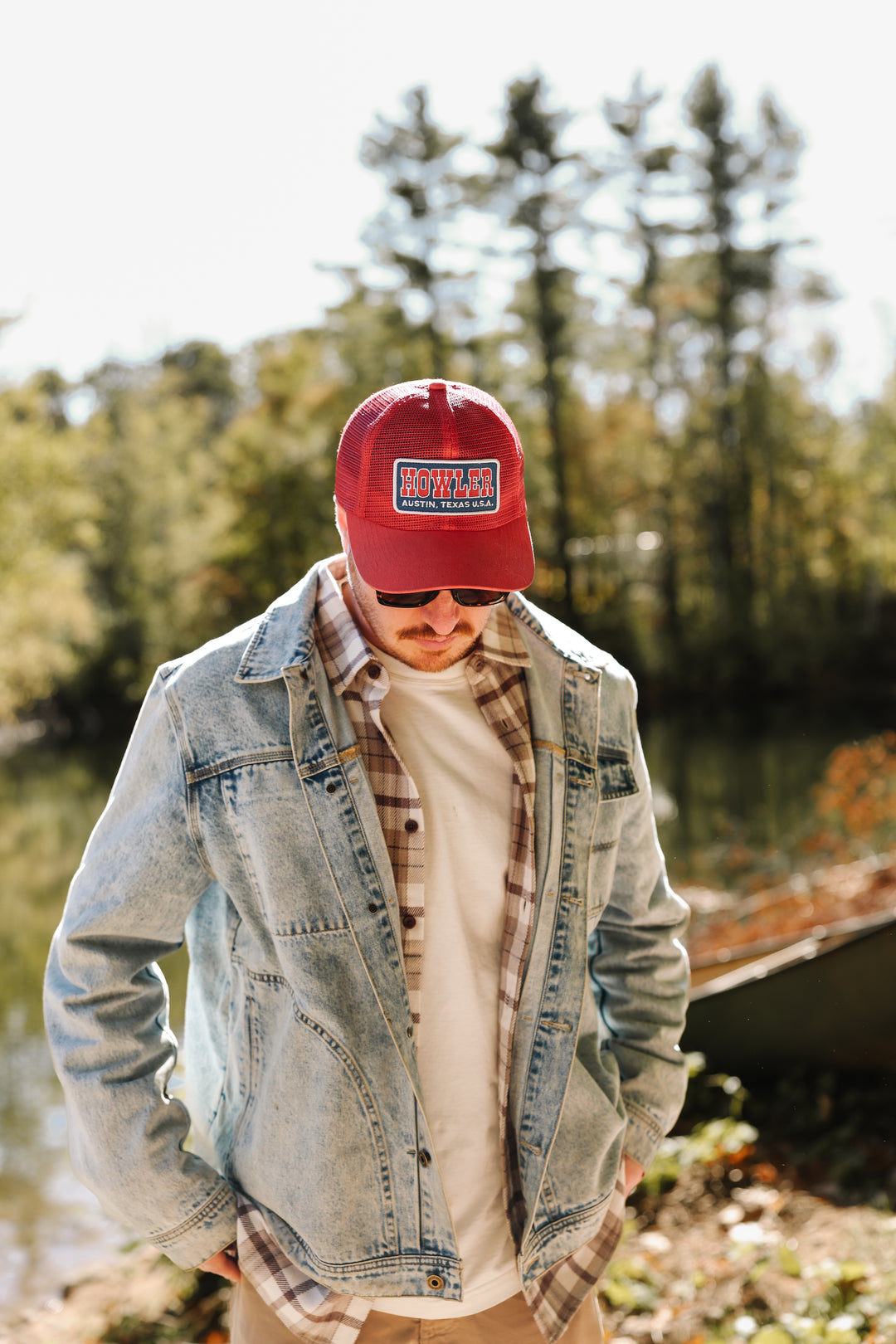 Person wearing a red cap and denim jacket outdoors with trees in the background