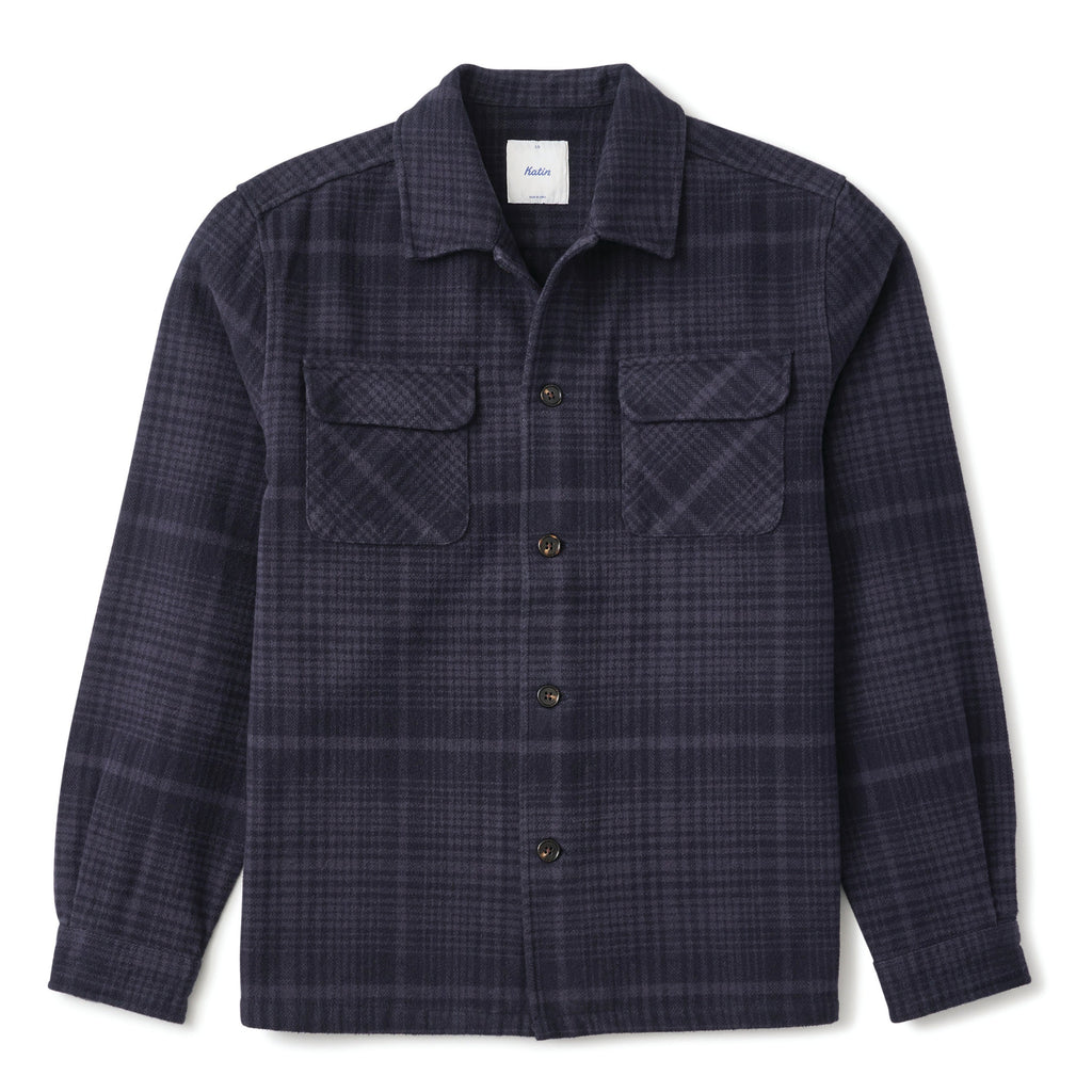 A dark navy plaid button-up shirt jacket with two chest flap pockets, displayed flat against a white background.