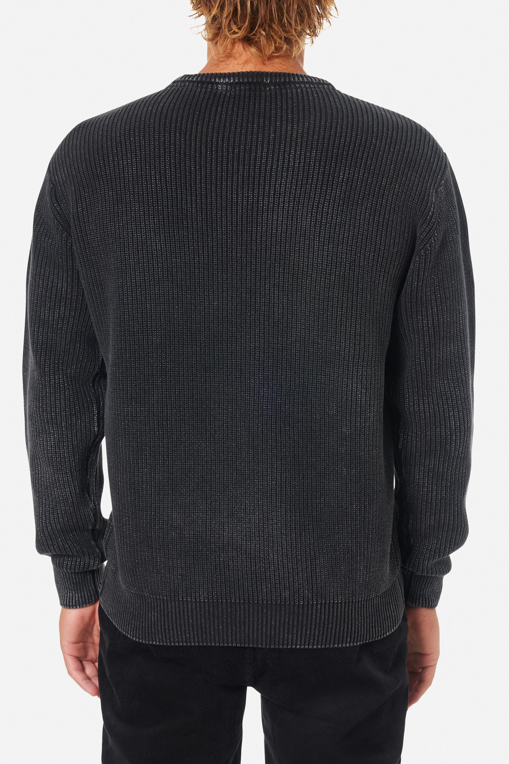 Person wearing a dark gray ribbed sweater on a white background
