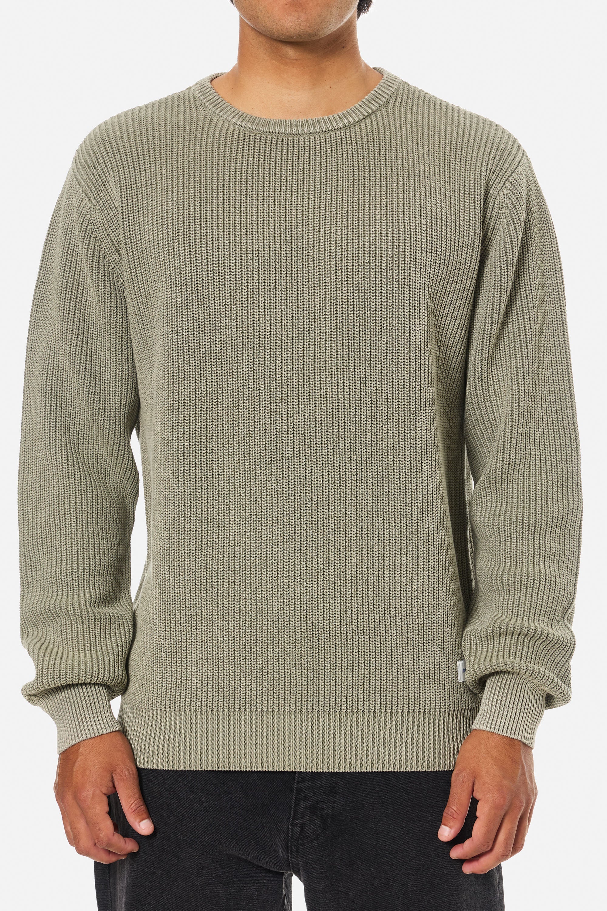 Person wearing a green ribbed sweater on a white background