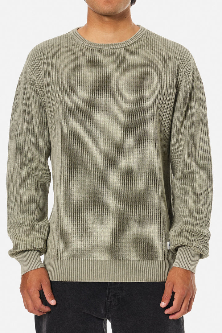 Person wearing a green ribbed sweater on a white background