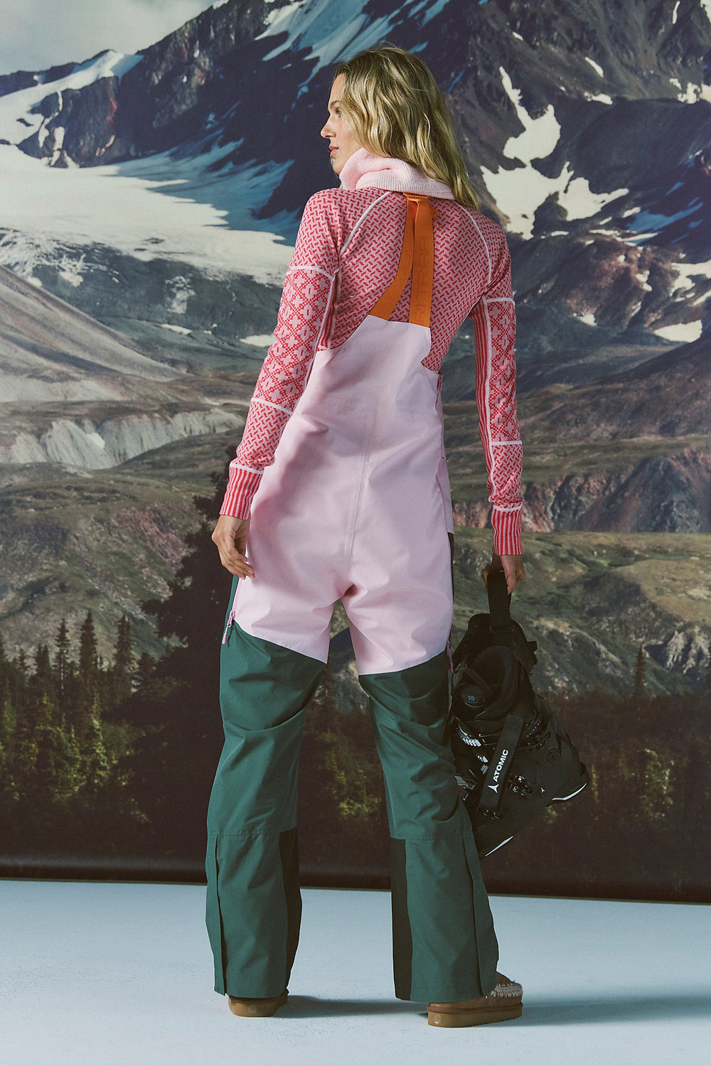 Person wearing pink and green snow pants with a mountainous landscape in the background