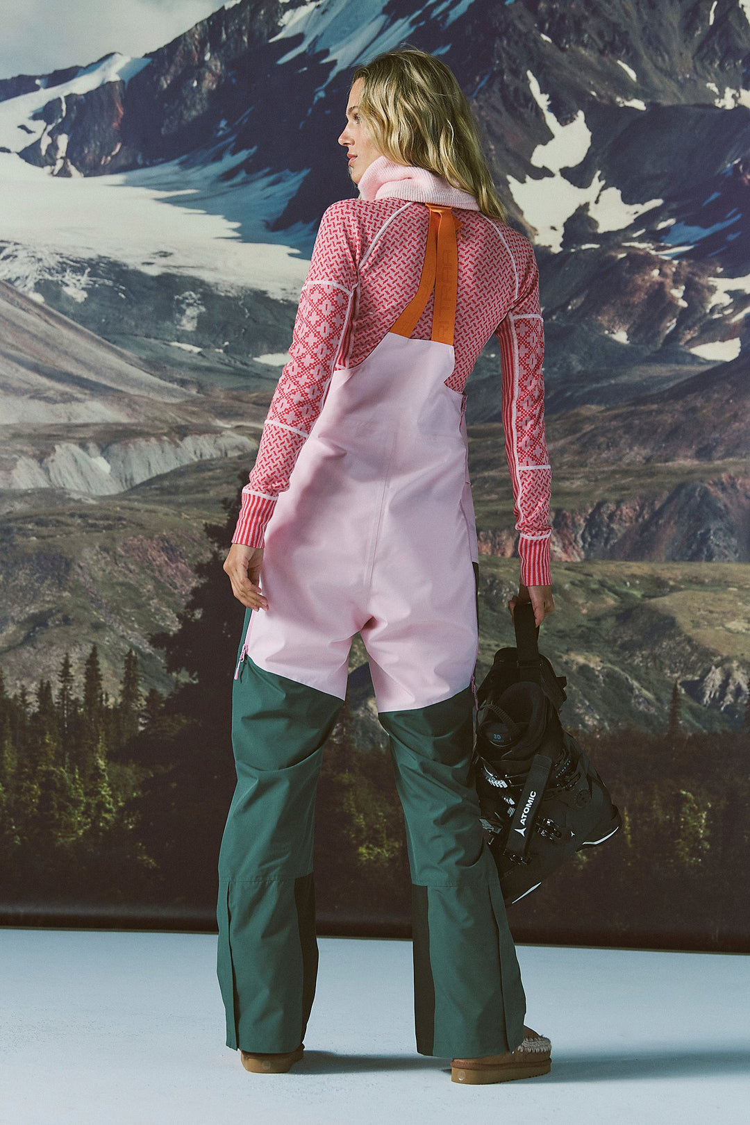 Person wearing pink and green snow pants with a mountainous landscape in the background