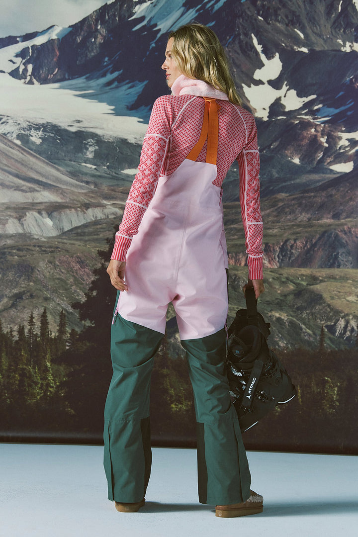 Person wearing pink and green snow pants with a mountainous landscape in the background