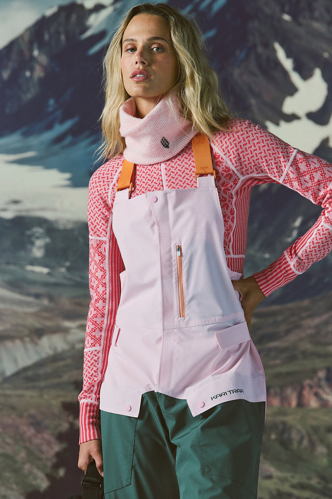 Person wearing a pink jacket and white apron with a mountainous background