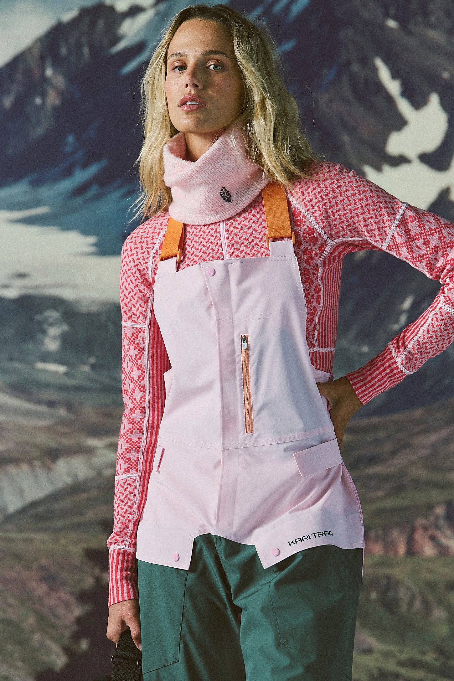 Person wearing a pink jacket and white apron with a mountainous background