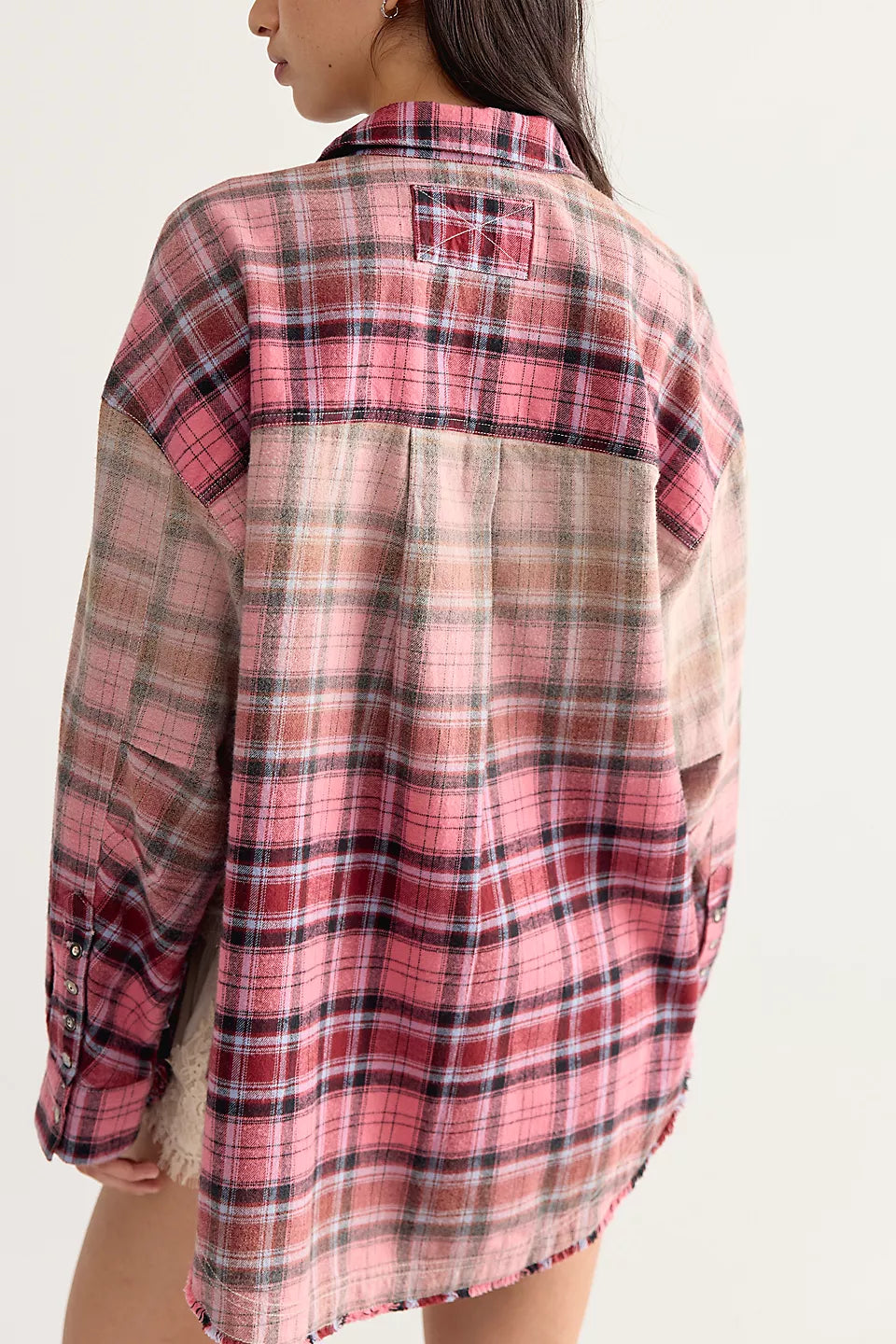 Back view of woman wearing pink plaid long sleeve shirt. White background