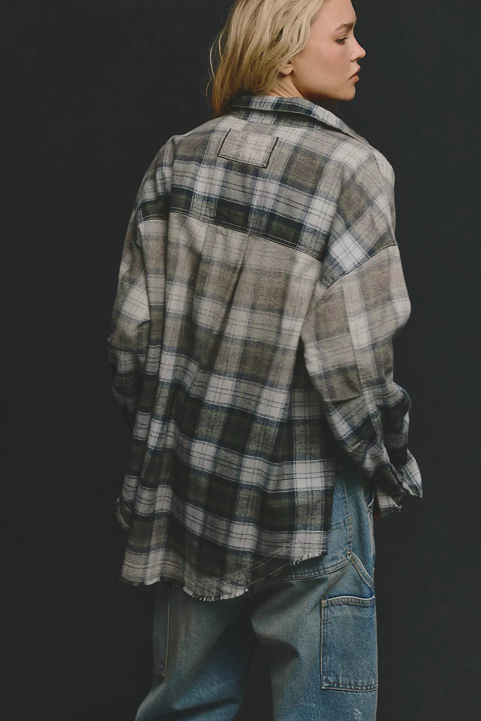 Woman model showing back of green and beige plaid long sleeve shirt paired with blue jeans. 