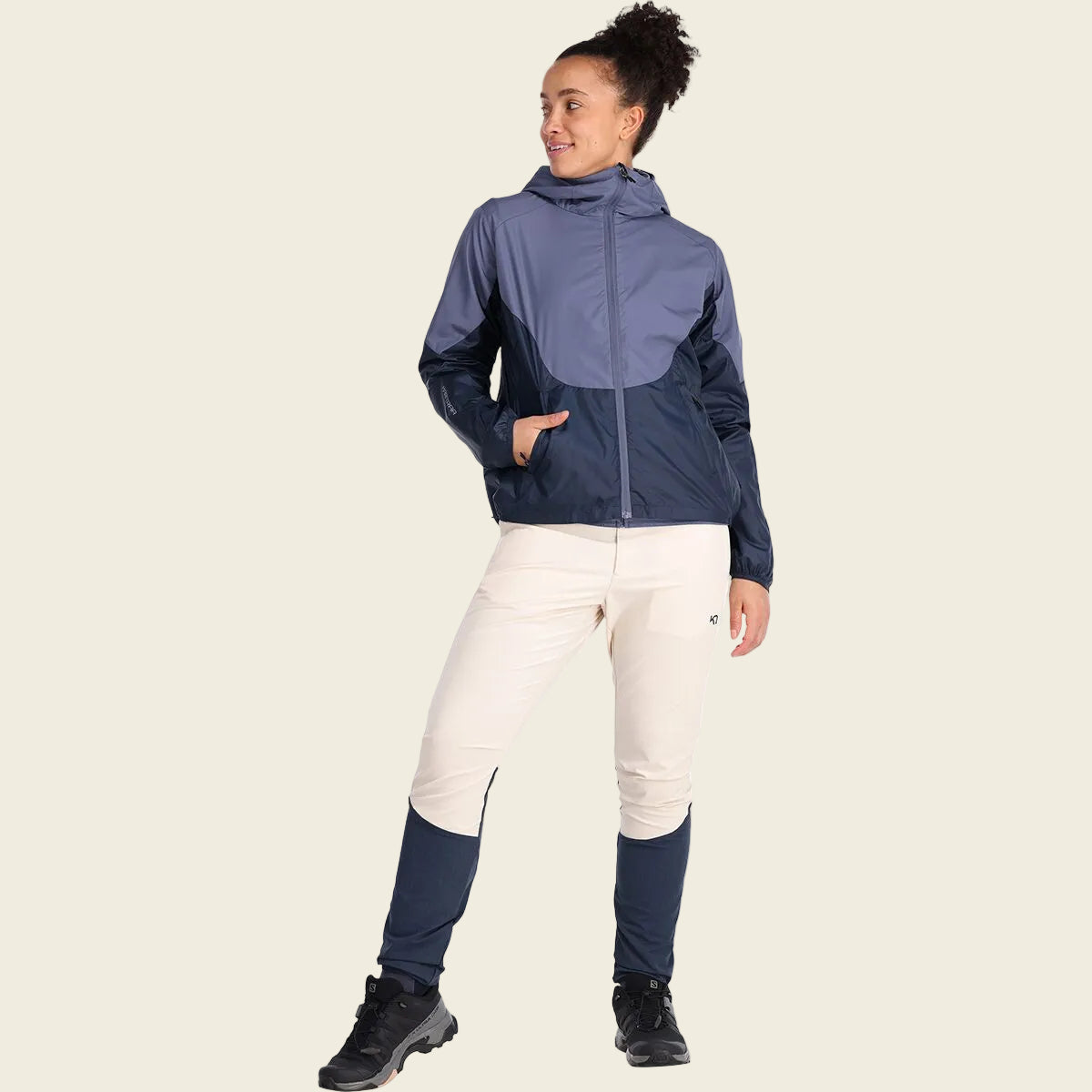 Person wearing a navy jacket, white pants, and black boots on a white background
