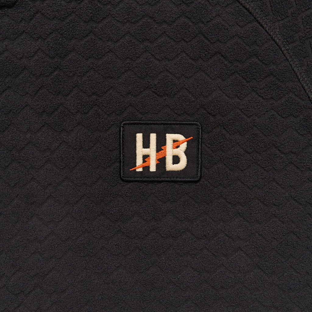 Black textured fabric with a logo patch featuring 'HB' on a black background