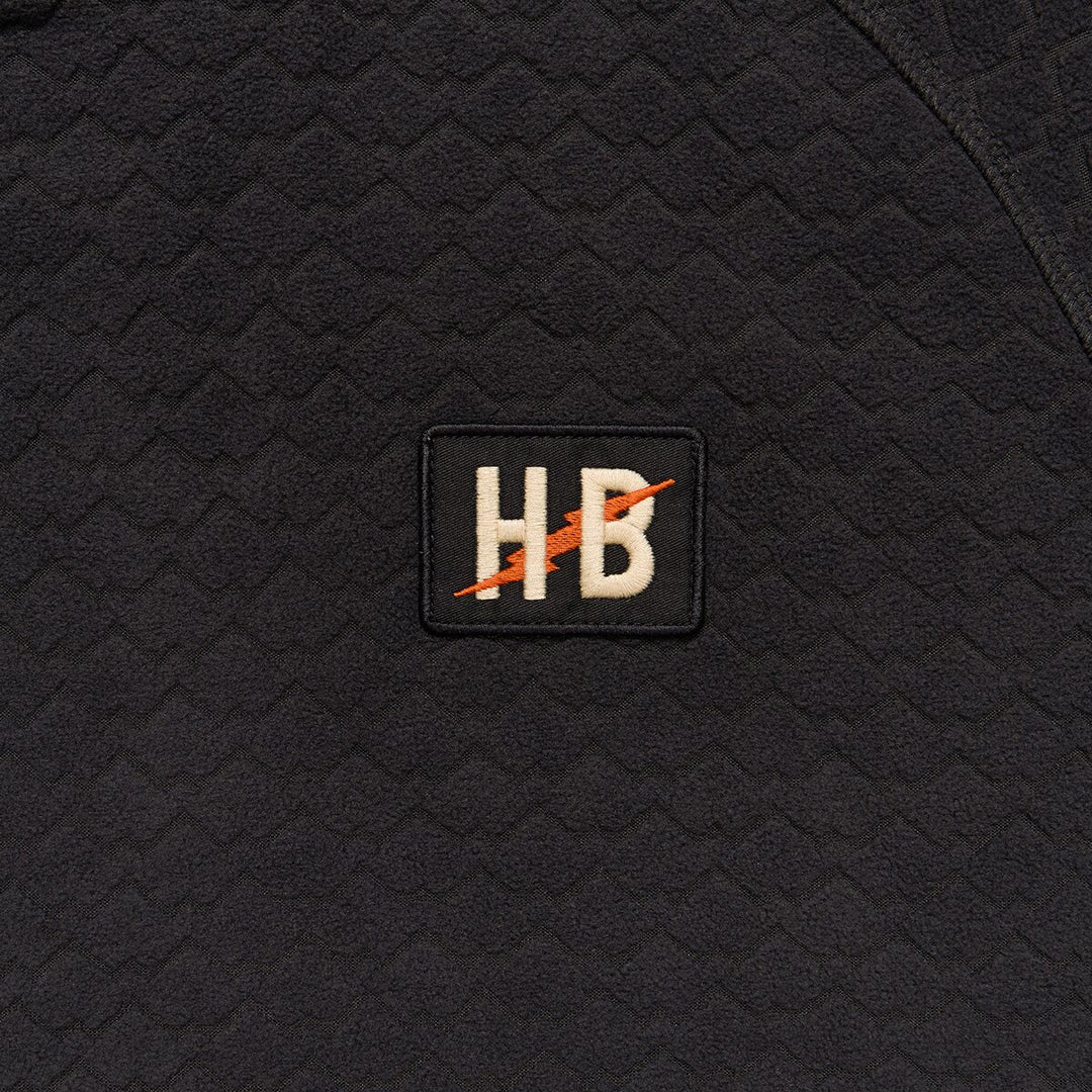 Black textured fabric with a logo patch featuring 'HB' on a black background