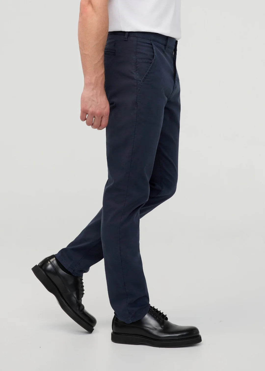 Person wearing navy pants and black shoes on a white background