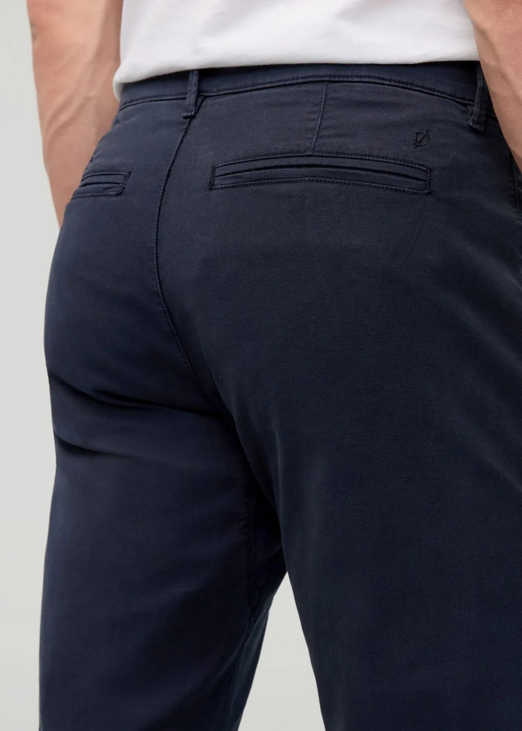 Navy pants worn by a person on a light gray background