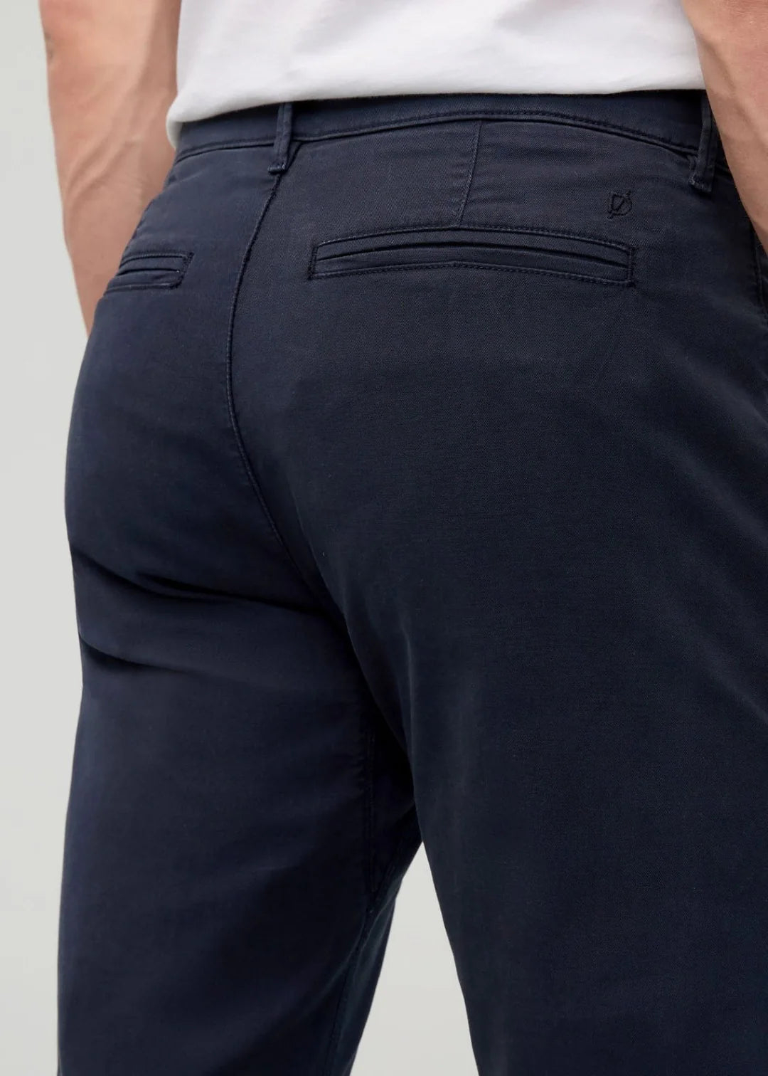 Navy pants worn by a person on a light gray background