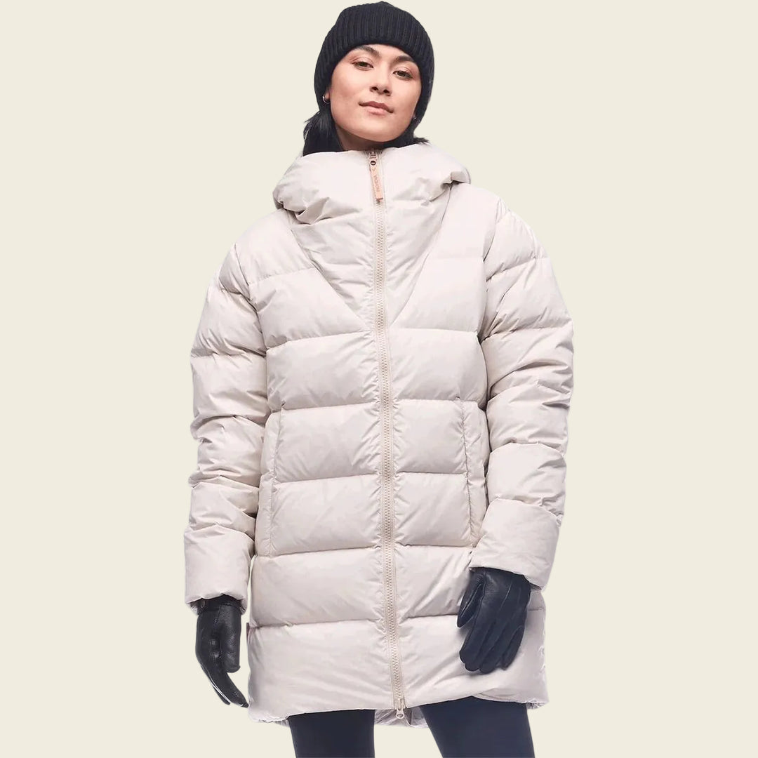 Person wearing a long beige puffer coat on a white background