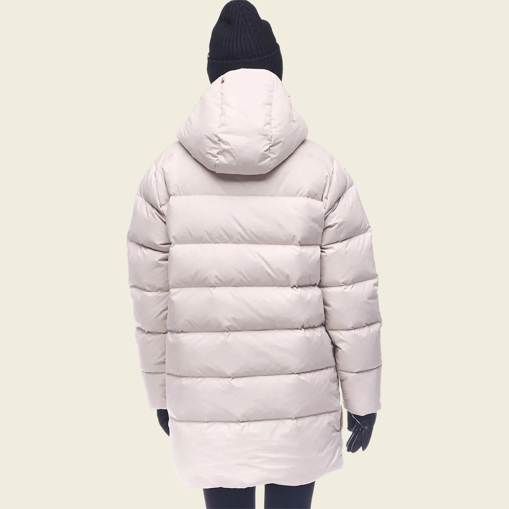 Person wearing a light pink puffer coat on a white background