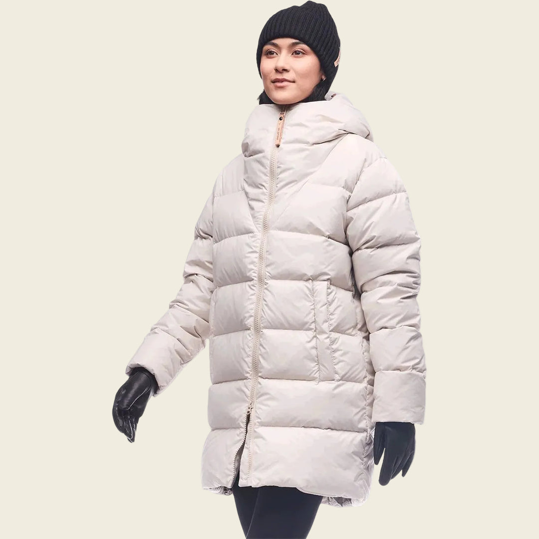 Person wearing a long beige puffer coat on a white background