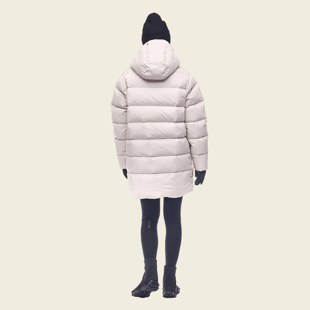 Person wearing a long beige puffer coat on a white background