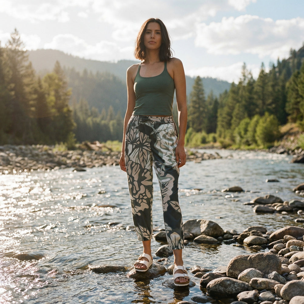 Woman standing by a river with mountains and trees in the background