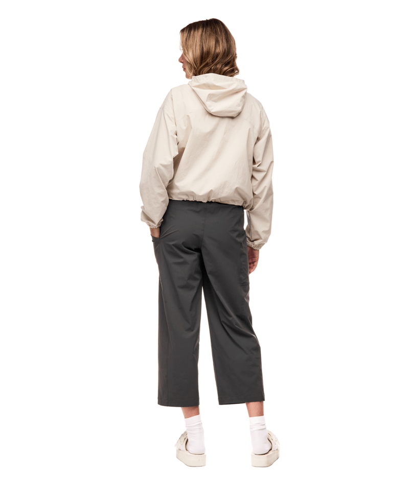 Person wearing a beige hoodie and gray pants on a white background