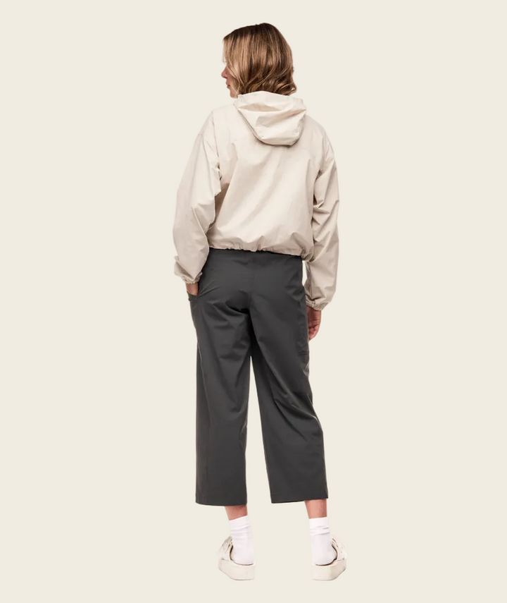 Person wearing a beige hoodie and gray pants on a white background