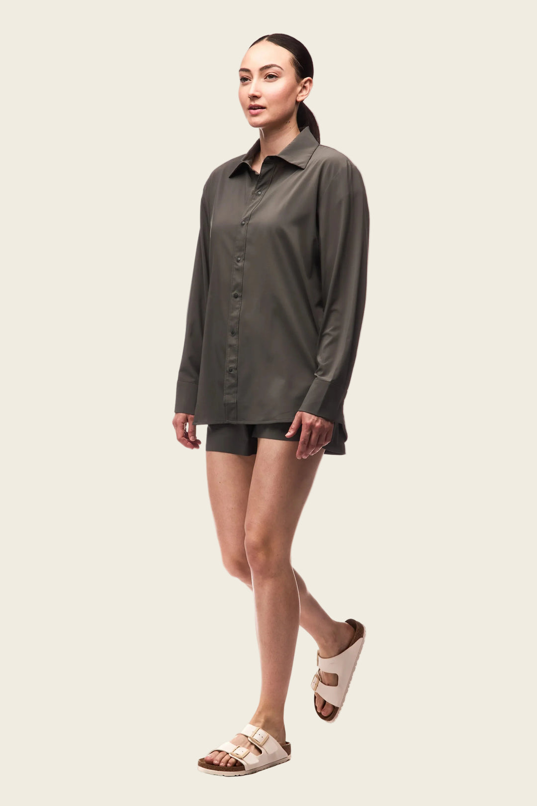 Woman wearing a gray shirt and shorts with sandals on a white background