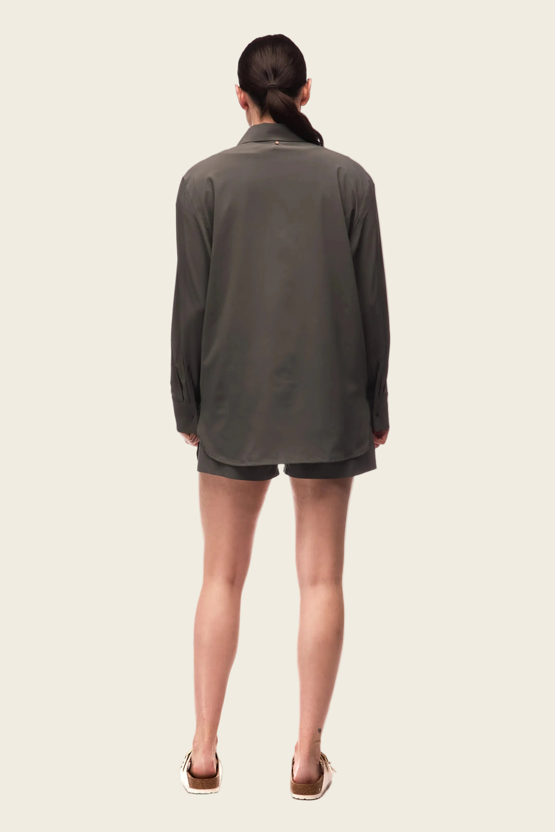 Person wearing a gray long-sleeve shirt and shorts on a white background