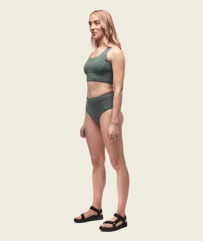 Woman wearing a green sports bra and shorts set on a white background