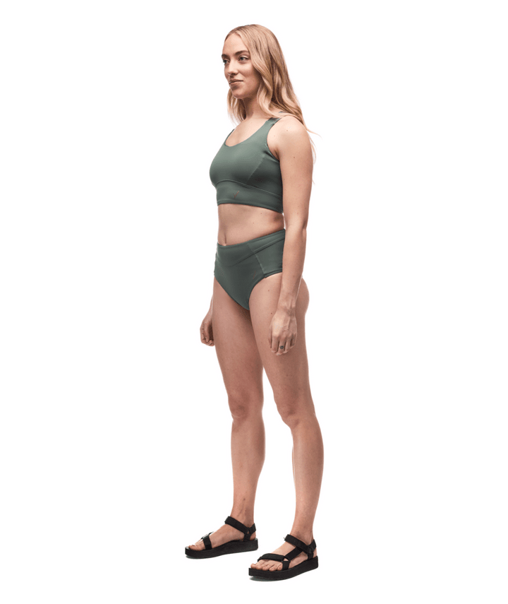 Woman wearing a green sports bra and shorts set on a white background