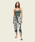 Woman wearing a green tank top and floral pants on a white background