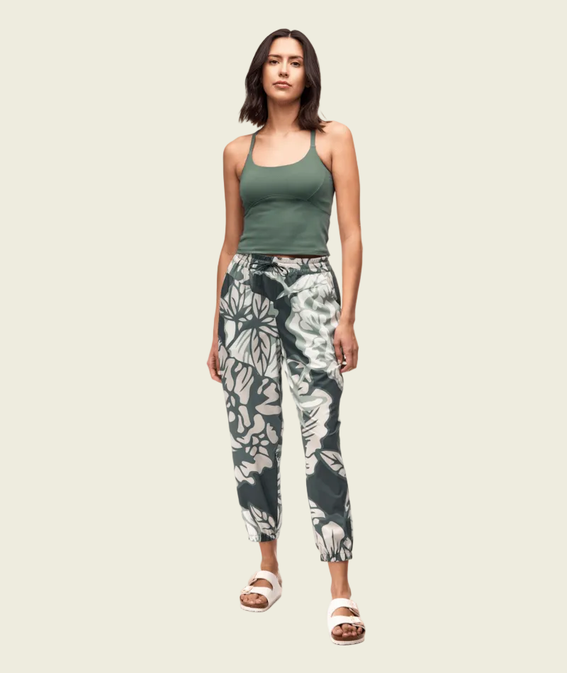Woman wearing a green tank top and floral pants on a white background