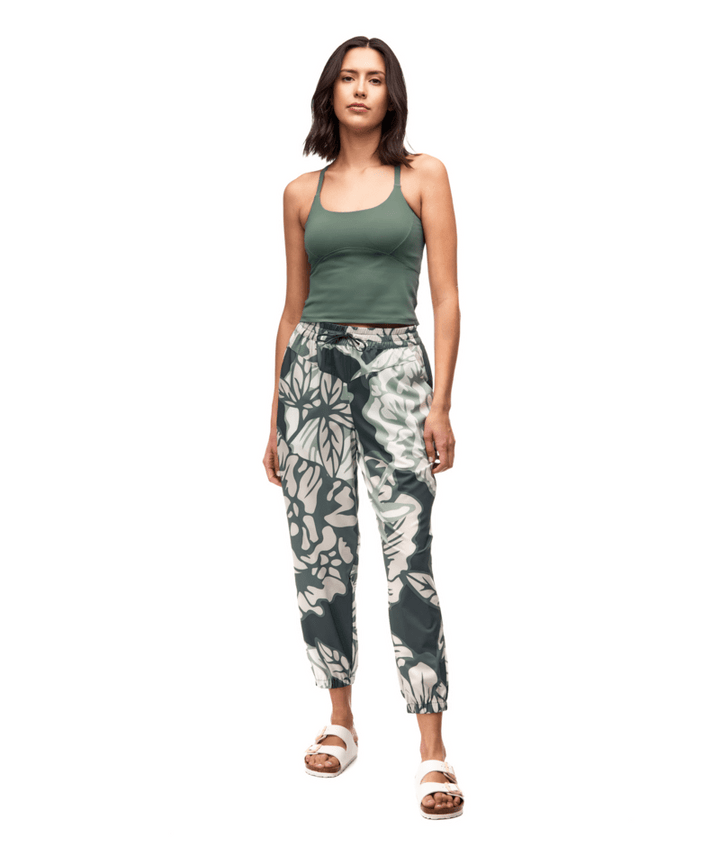 Woman wearing a green tank top and floral pants on a white background