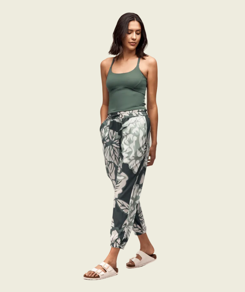 Woman wearing a green tank top and patterned pants on a white background