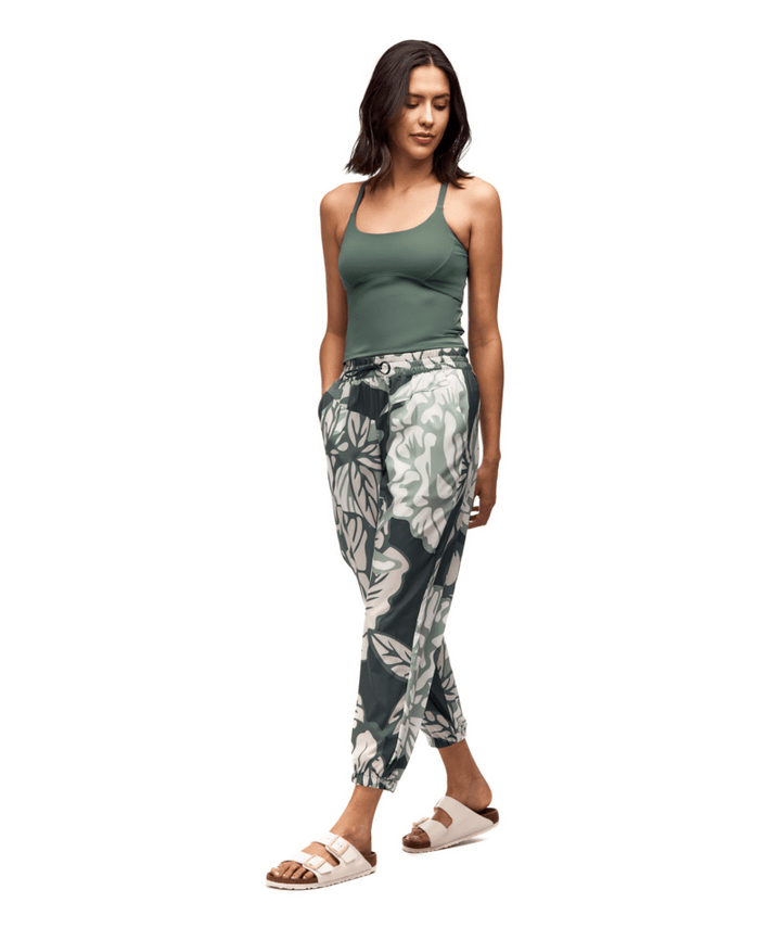 Woman wearing a green tank top and patterned pants on a white background