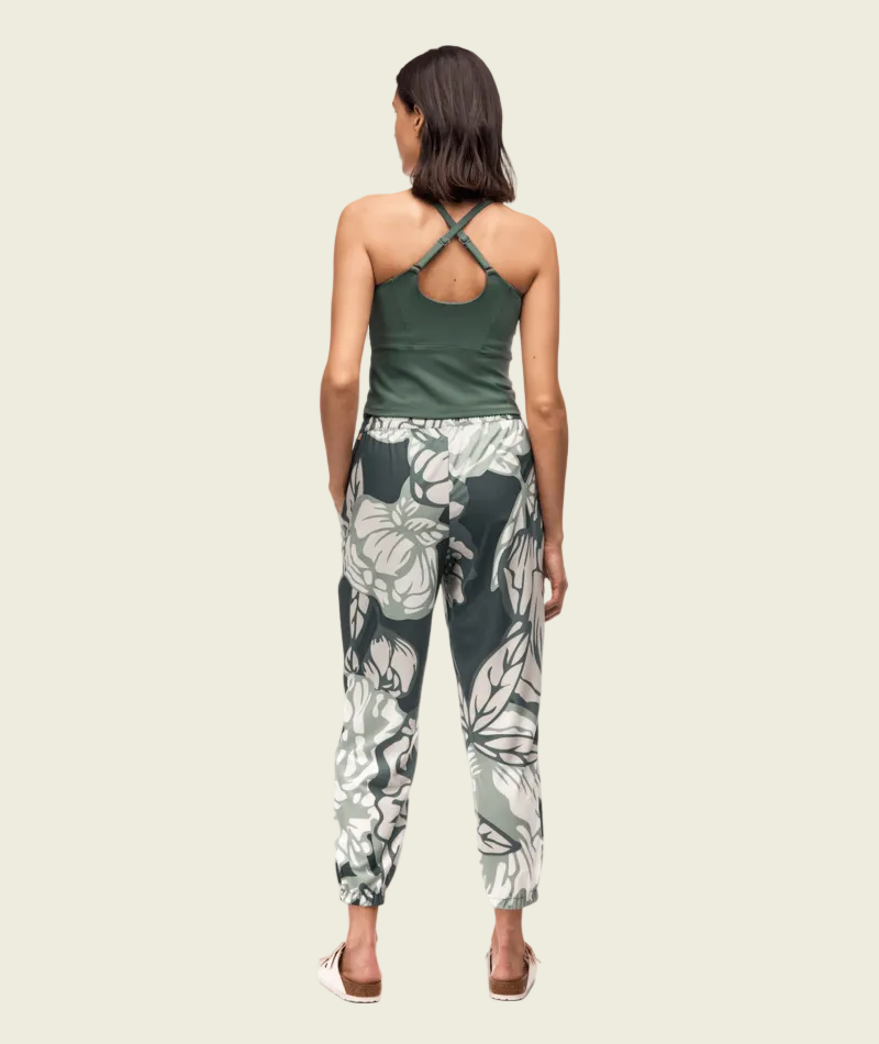 Woman wearing a green tank top and floral pants on a white background