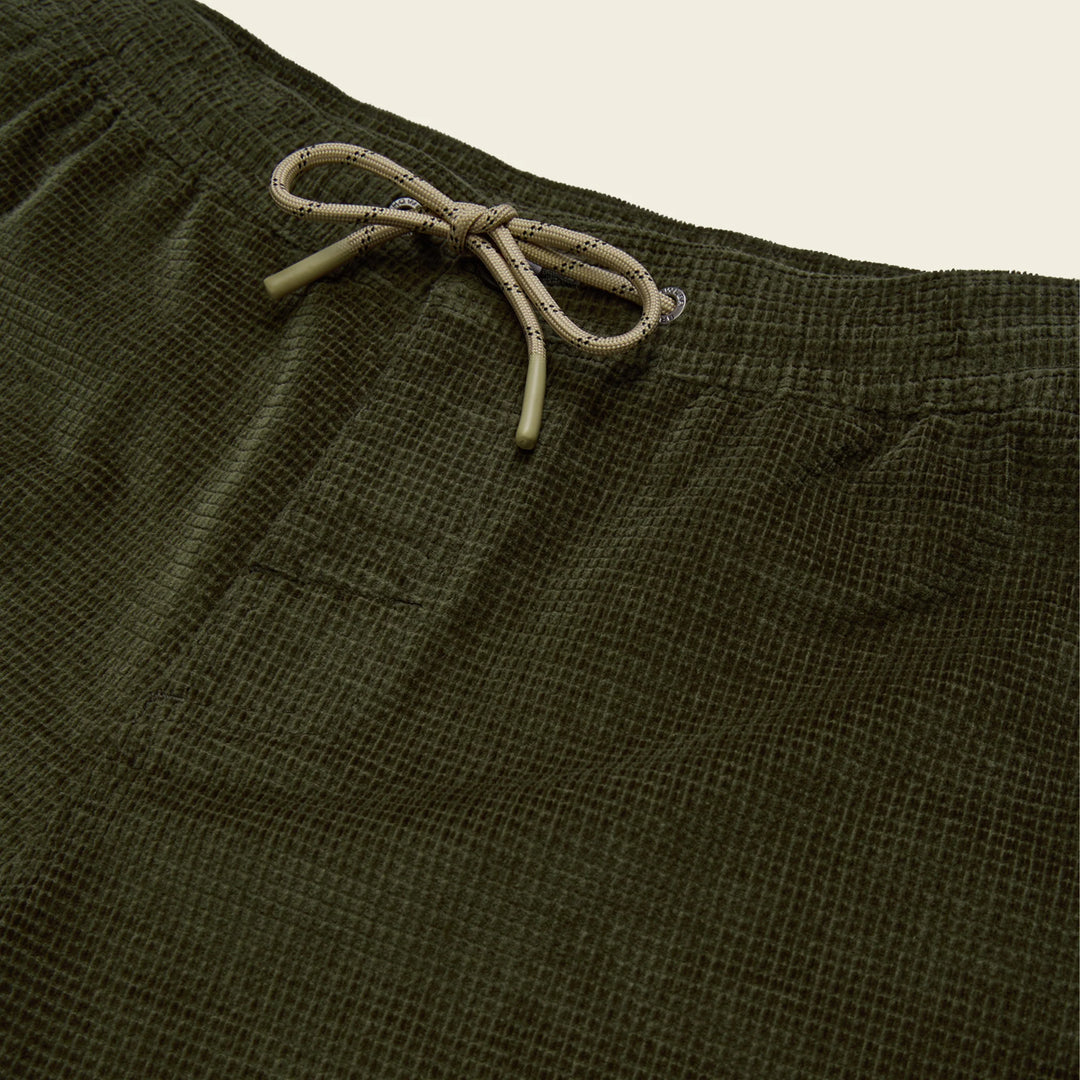 Close-up of olive green shorts with a drawstring on a beige background