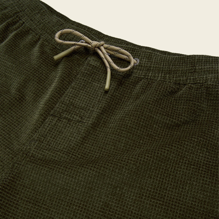 Close-up of olive green shorts with a drawstring on a beige background