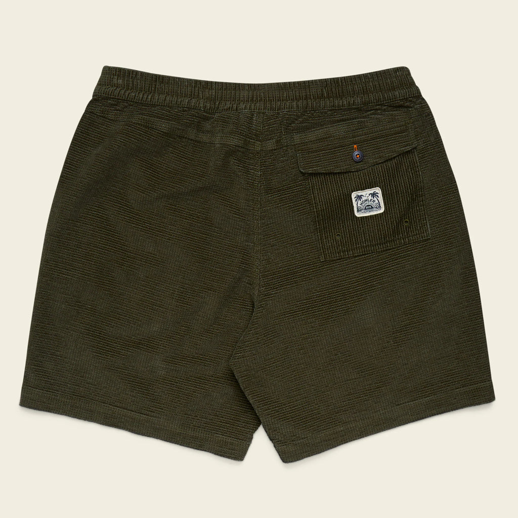 Green shorts with a logo on the pocket against a beige background