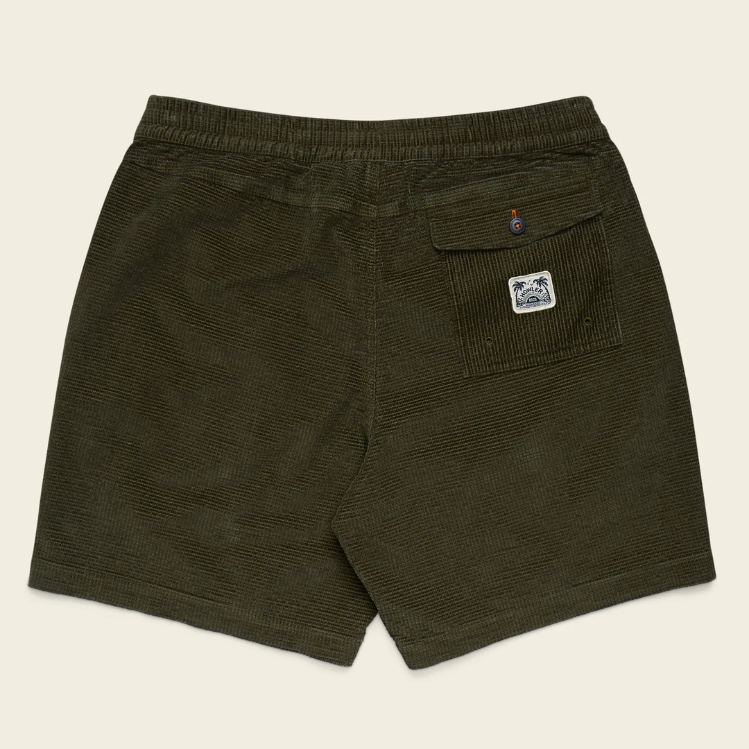 Green shorts with a logo on the pocket against a beige background