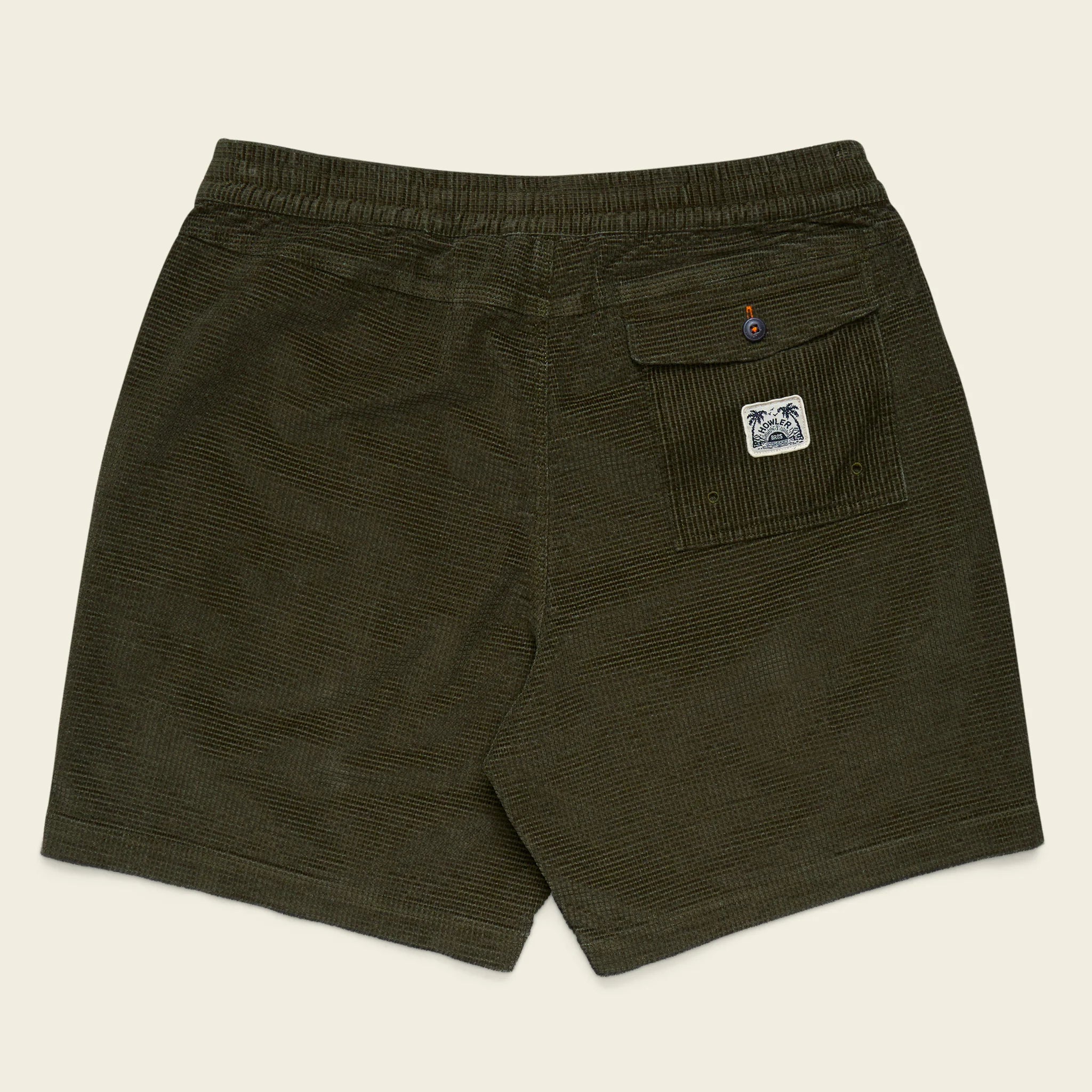 Green shorts with a logo on the pocket against a beige background