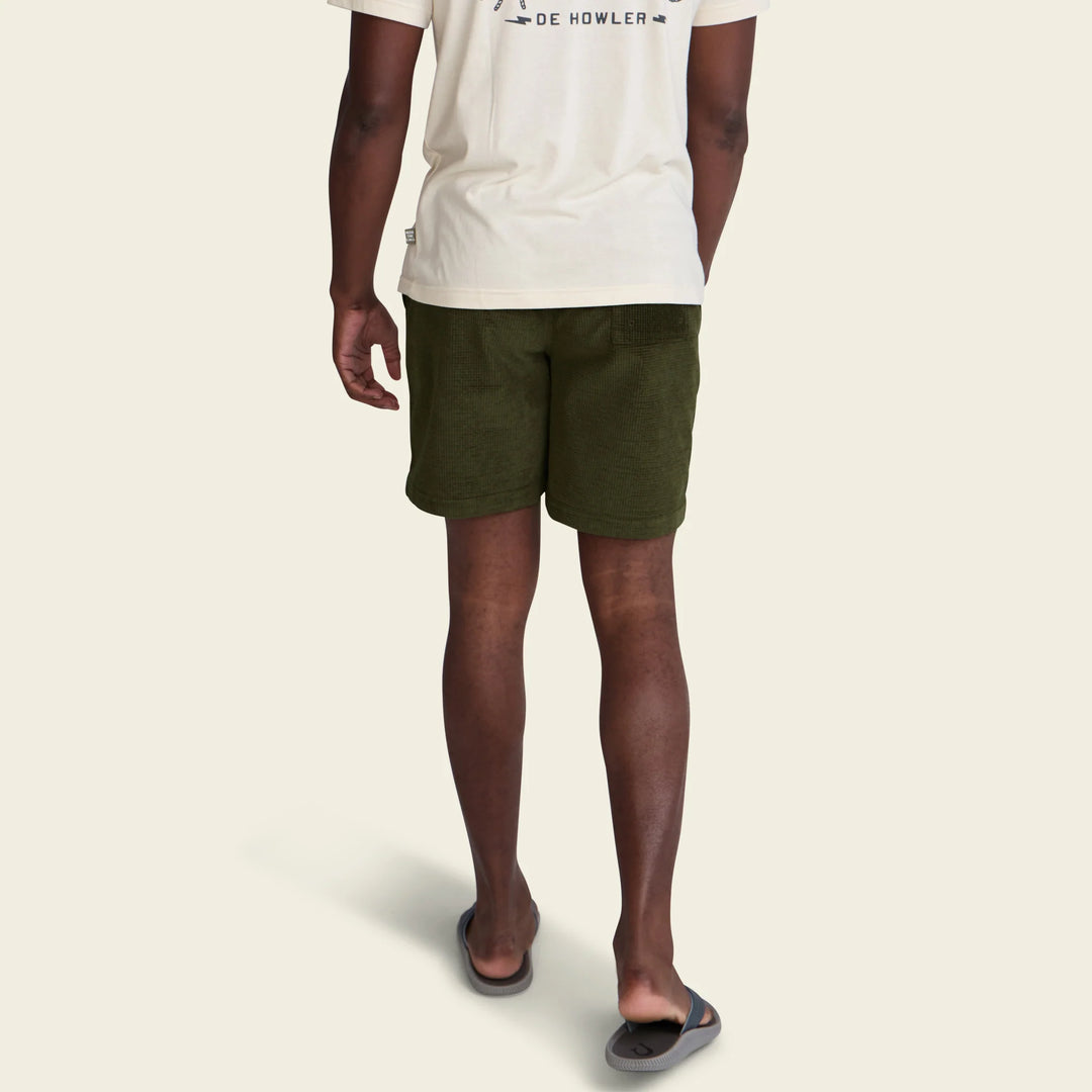 Person wearing green shorts and a white t-shirt on a beige background