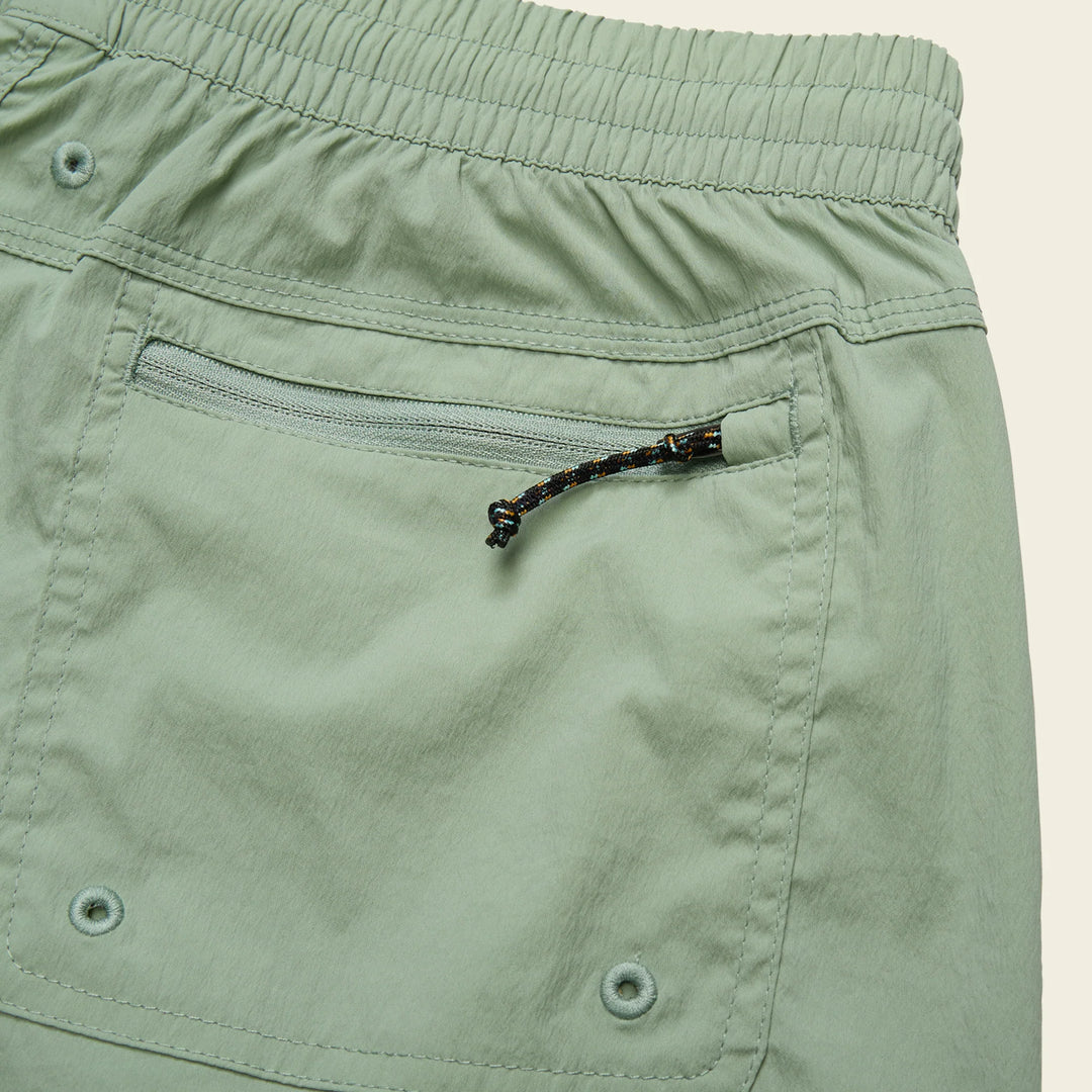 Close-up of green shorts with a zipper pocket on a beige background