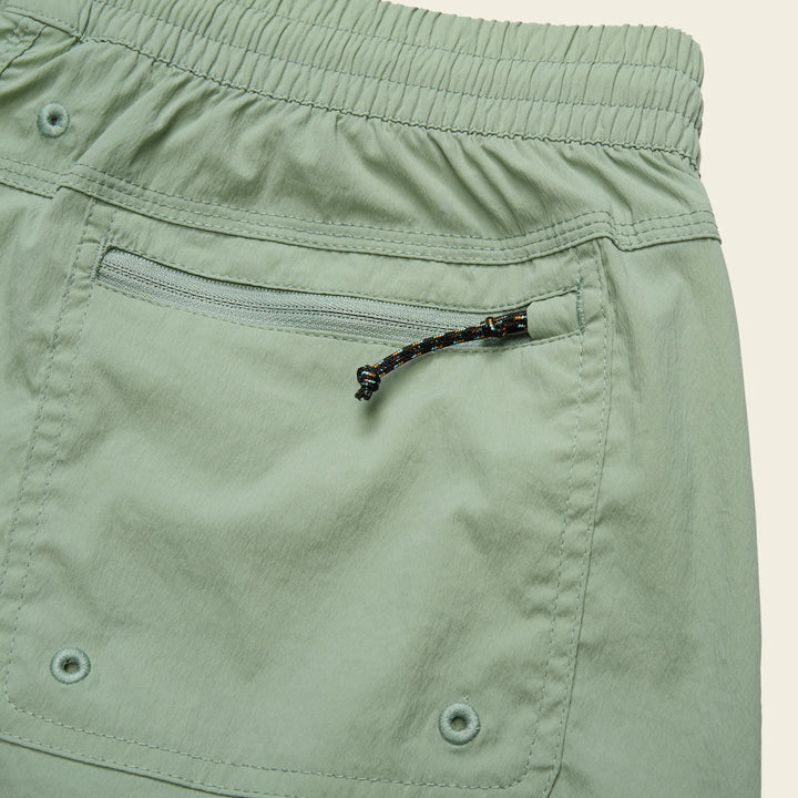 Close-up of green shorts with a zipper pocket on a beige background
