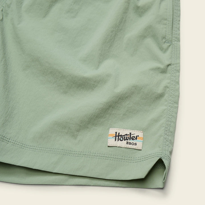 Close-up of a green shorts with a brand label on a white background