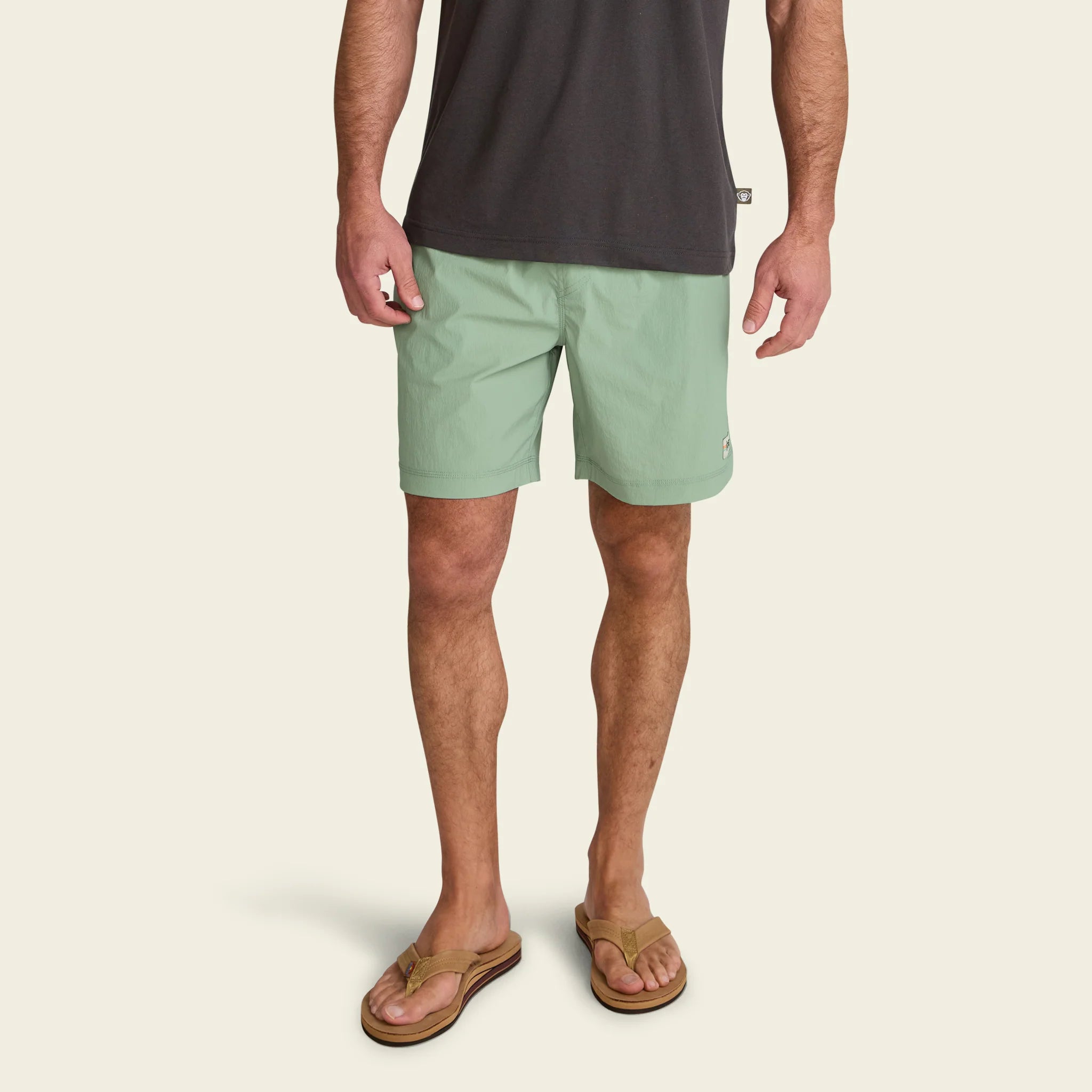 Person wearing light green shorts and a dark shirt on a beige background