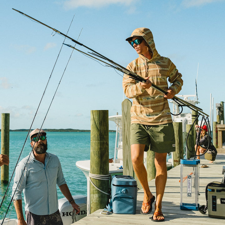 Two men on a dock by the water, one holding a fishing rod.