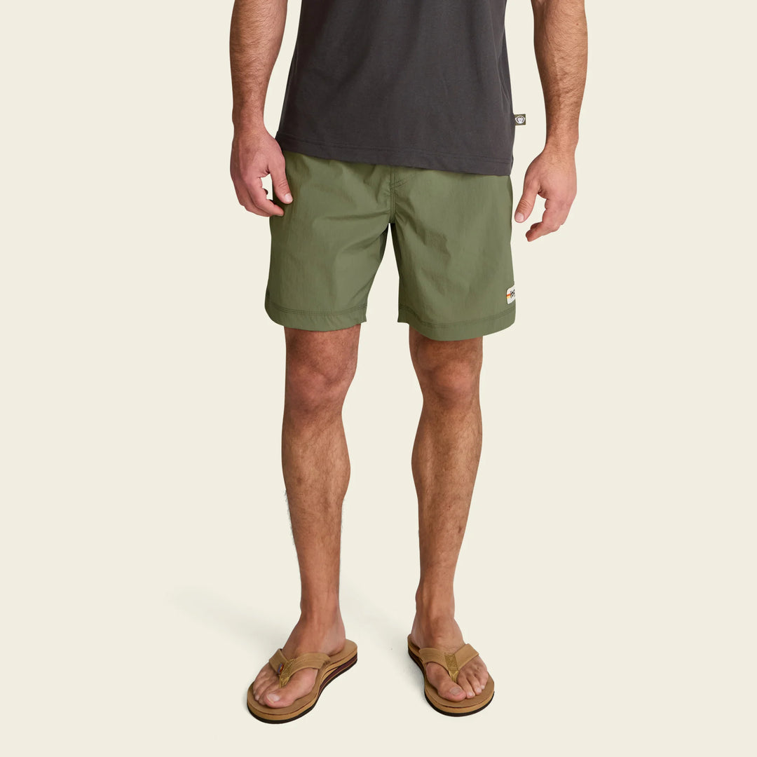 Person wearing green shorts and a dark shirt on a beige background